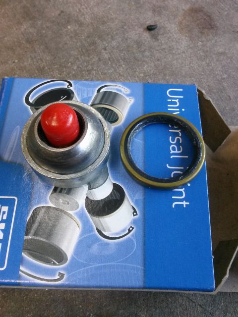 1996 Ford Bronco - A new universal joint and a seal are laid out on top of a blue box with "Universal Joint" printed on it. The universal joint has a silver m…