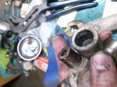 1996 Ford Bronco - A close-up shot shows a person holding a greasy automotive CV joint with splines visible in the socket and on the shaft. Tools and other pa…