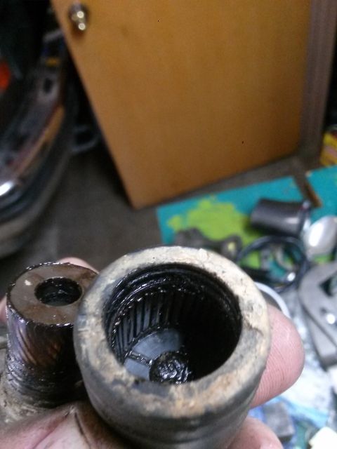 1996 Ford Bronco - A close-up of two greasy, splined metal parts, likely from a vehicle's drivetrain, held in a person's hand.