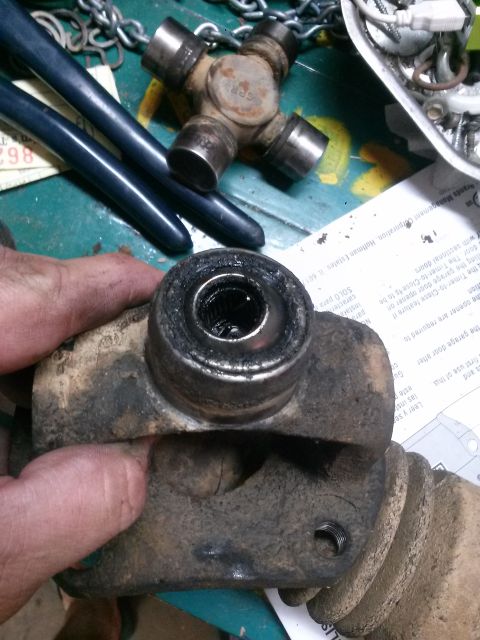 1996 Ford Bronco - A close-up shot shows a worn-out universal joint, likely from a 1996 Ford Bronco, being held in a hand. The U-joint appears dirty and has a…