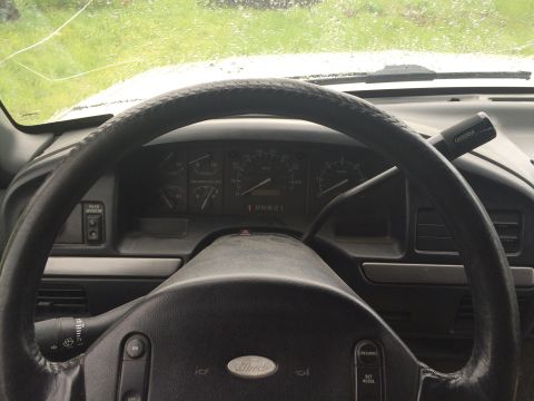 1993 Ford Bronco - The interior of a vintage Ford Bronco shows the steering wheel, dashboard gauges, and gear shifter. The windshield is visible in the backgr…