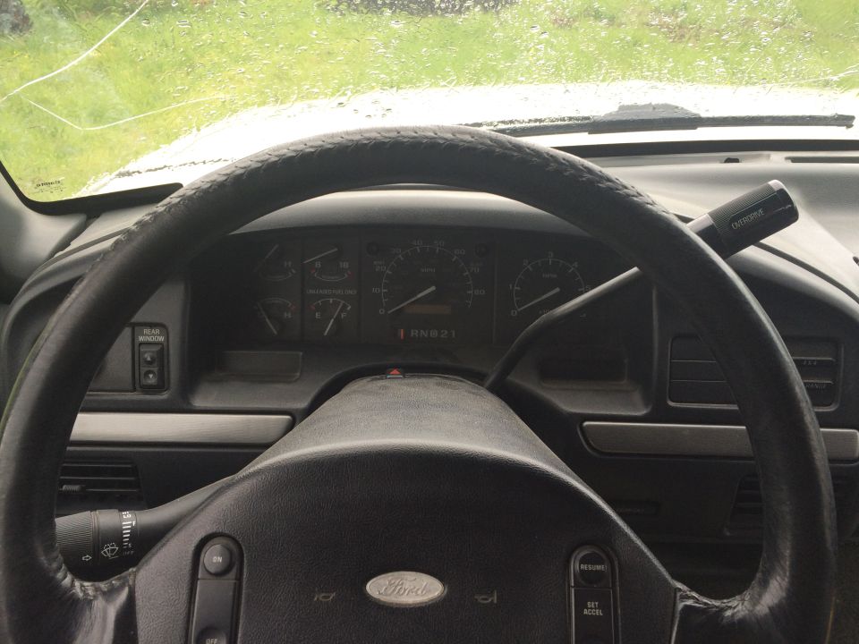 Interior view of a Ford Bronco dashboard and steering wheel with rain on the windshield.