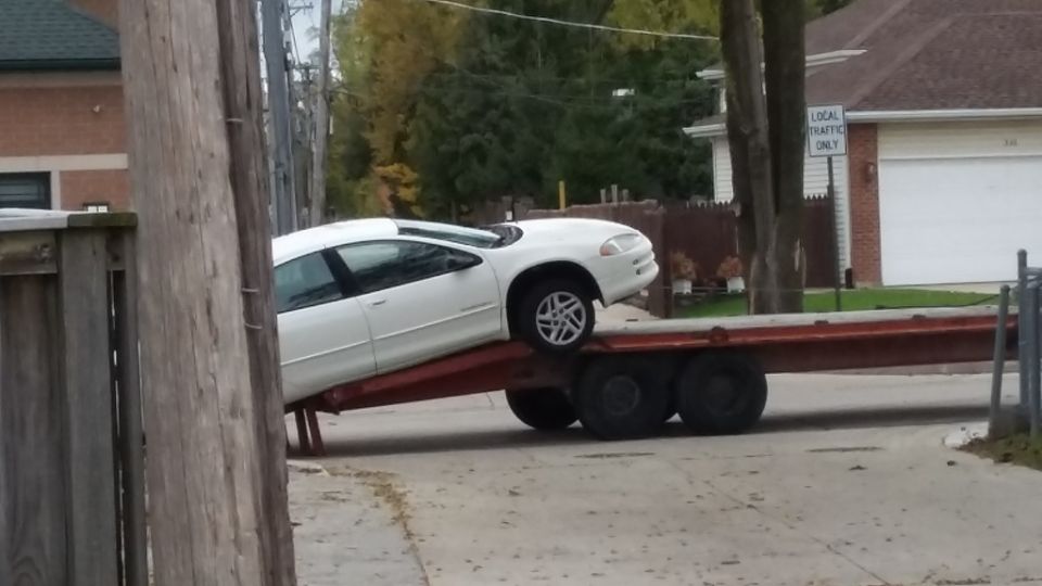 White sedan on a red car trailer ramp.