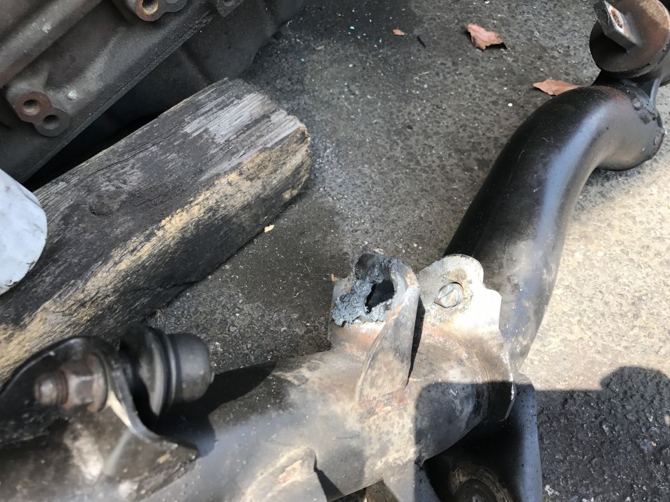 Damaged black metal suspension part with rust and a broken section.