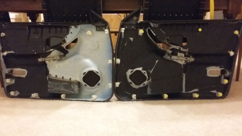 Two car door panels, interior side, one light gray, one black, with speakers visible.