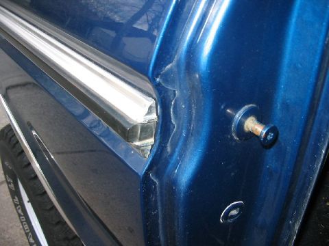1978 Ford Bronco - A close-up shot focuses on the door trim and lock mechanism of a blue vehicle.