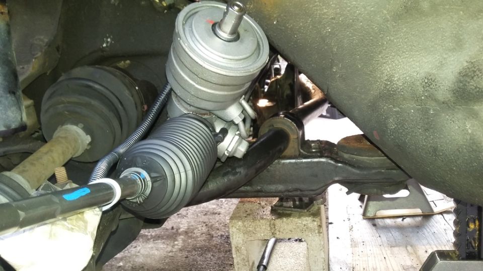 Close-up of a car's steering rack and pinion assembly with a new tie rod end.