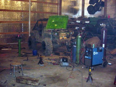 1992 Ford Bronco - An off-road vehicle is in a garage, surrounded by tools and welding equipment, with its hood open.