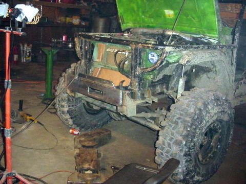 1992 Ford Bronco - This green off-road vehicle is in a garage, possibly undergoing modifications, with its hood open and a custom bumper installed.