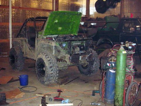 1992 Ford Bronco - A Suzuki Samurai is undergoing work in a garage, with a pickup truck visible in the background.