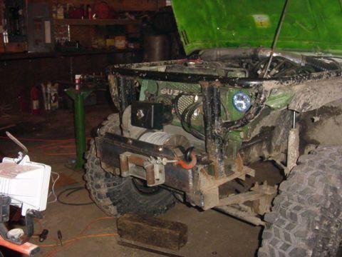 1992 Ford Bronco - The front of a green Suzuki Samurai is shown with its hood up, revealing the engine bay and a winch mounted on the bumper.