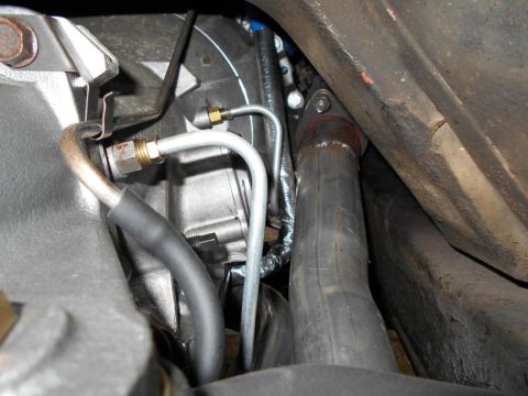 1974 Ford Bronco - Close-up view of engine bay components, including brake lines and exhaust system.