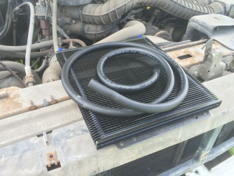 1993 Ford Bronco - New transmission cooler and hoses laid out in the engine bay of a vehicle.