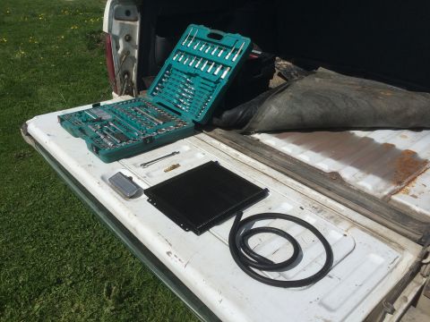 1993 Ford Bronco - Tools and parts are organized on the tailgate of a pickup truck, ready for a repair or project.