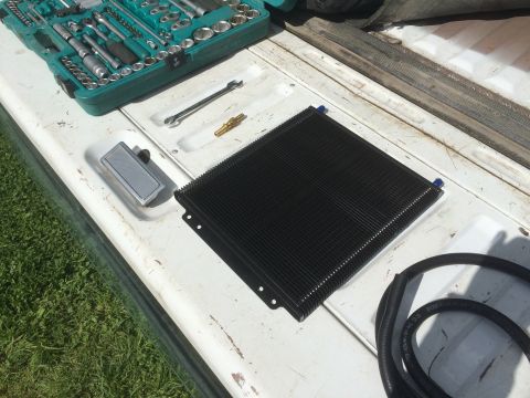 1993 Ford Bronco - A collection of tools and a transmission cooler are laid out on the bed of a white truck.