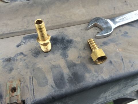 1993 Ford Bronco - Brass fittings and a wrench are placed on a dirty surface, possibly during a repair or maintenance task.