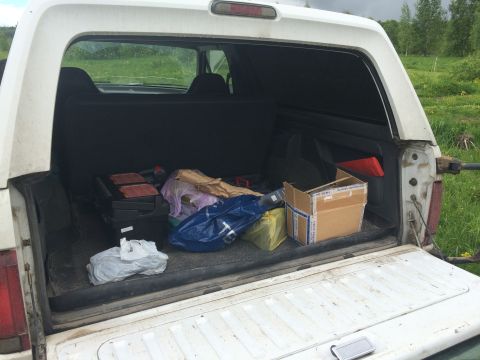 1993 Ford Bronco - The cargo area of a white SUV is filled with assorted items, including boxes and bags, with a grassy field visible in the background.