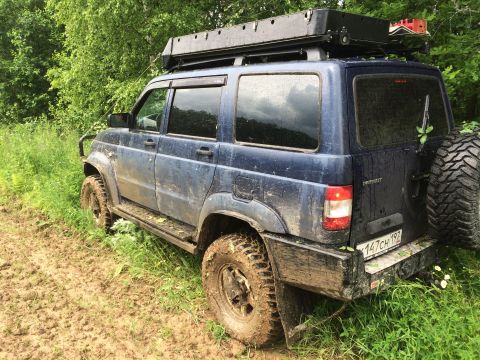 1993 Ford Bronco - Off-road SUV with roof rack and spare tire is stuck in muddy terrain.