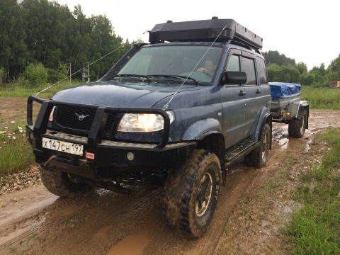 1993 Ford Bronco - This UAZ Patriot SUV is equipped for off-road adventures, complete with a roof rack and towing a trailer through muddy terrain.