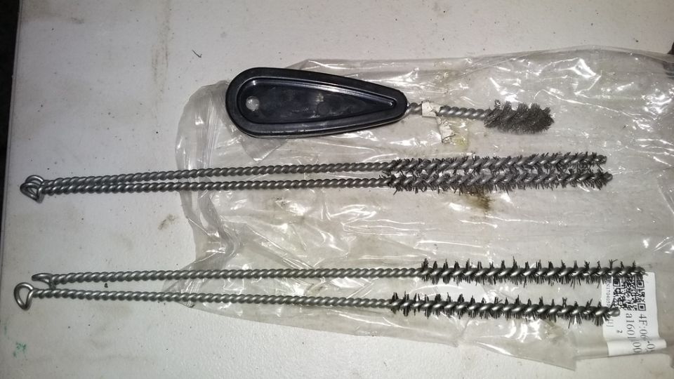 Set of wire cleaning brushes with a black handle, some appear used