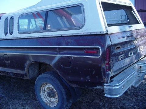 1992 Ford Bronco - Rear view of a 1979 Ford F-150 pickup truck fitted with a white camper shell. The vehicle shows signs of wear and tear.