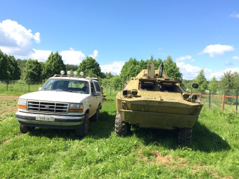 1993 Ford Bronco - A 1993 Ford Bronco is parked next to a military armored vehicle under a clear blue sky.