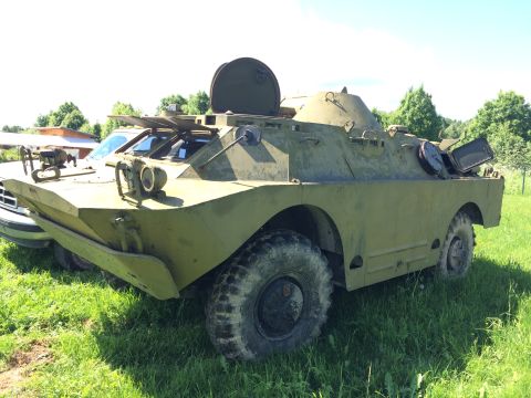 1993 Ford Bronco - An olive drab armored personnel carrier sits in a grassy field next to a white pickup truck.