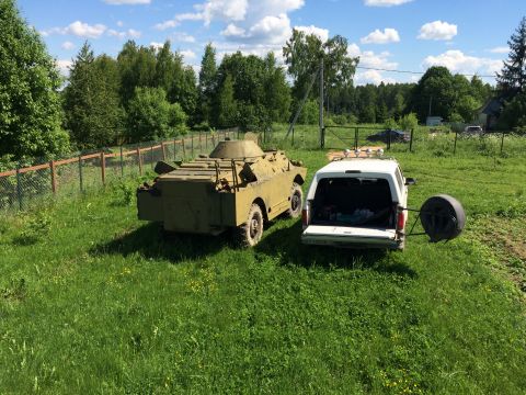 1993 Ford Bronco - A white SUV and a military vehicle are parked in a grassy field on a sunny day.