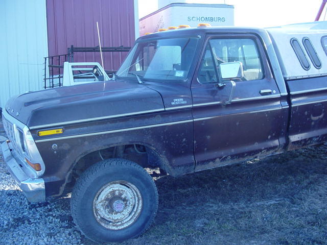 Side view of a dark red 1977 Ford F-Series truck with a white camper shell. Another white vehicle is partially visible behind it
