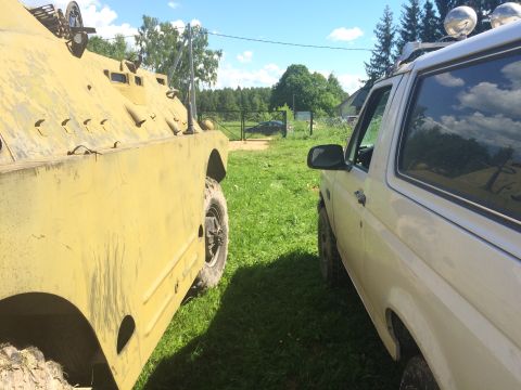 1993 Ford Bronco - A 1993 Ford Bronco is parked next to a military vehicle in a grassy area.