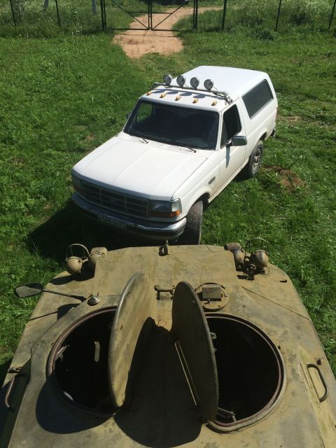 1993 Ford Bronco - A white 1993 Ford Bronco is parked in a grassy area next to a military vehicle.