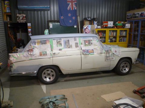 1962 MG B - A station wagon is covered in newspaper and tape, undergoing preparation for a paint job in a garage.