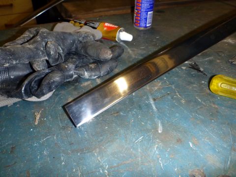1962 MG B - A chrome trim piece is on a workbench next to tools and supplies.