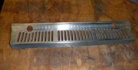1962 MG B - A metal grille part, likely from a vehicle, is shown against a wooden background.