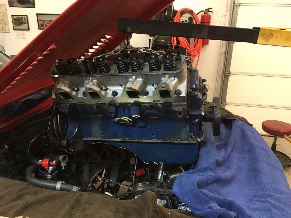 Engine with valve covers removed, being lifted by an engine hoist