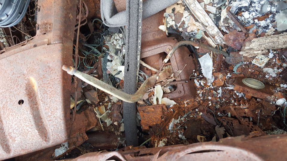 Rusted interior of a vehicle with debris and wiring visible