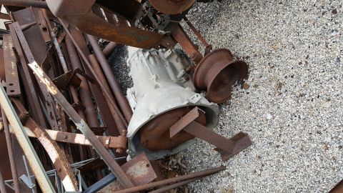 1973 Ford F-100 - A pile of scrap metal and a transmission are shown on a gravel surface.