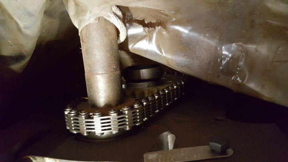 close-up of engine timing chain and gears, partially covered by plastic sheeting
