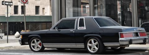 1985 Mercury Grand Marquis - 1985 Mercury Grand Marquis with custom wheels and red brake calipers parked curbside.