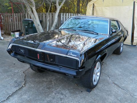 1969 Mercury Cougar - A black 1969 Mercury Cougar is shown from the front 3/4 angle, parked outdoors.