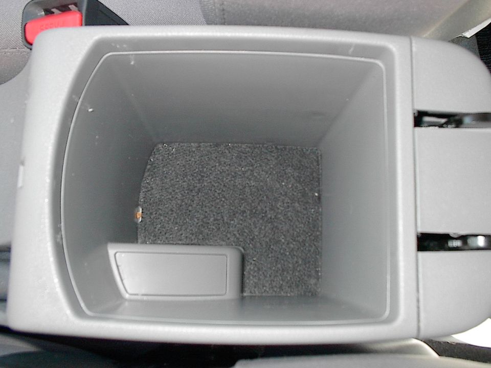 Open empty gray center console storage bin with carpeted bottom in a car interior