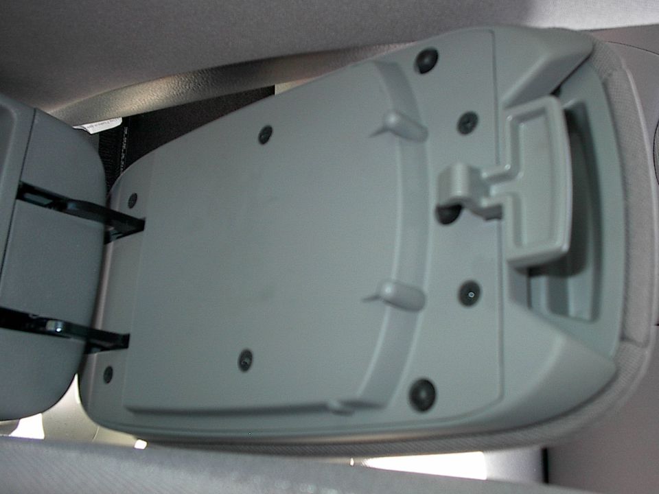 Gray plastic flip-up center console lid open inside a vehicle interior