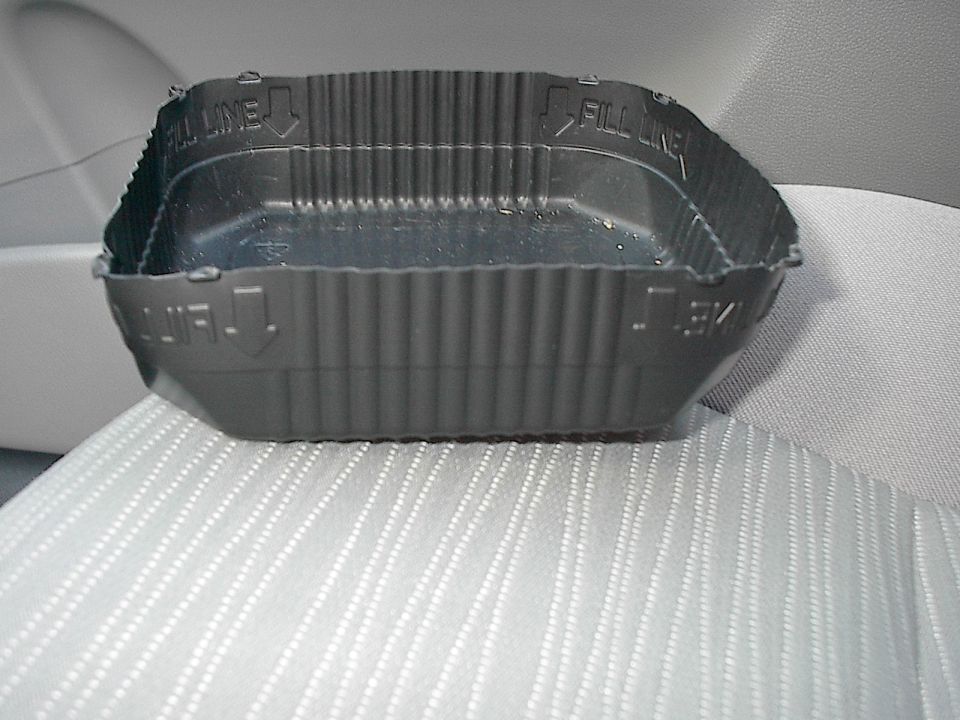 Black plastic tray marked 'FILL LINE' resting on a gray fabric car seat