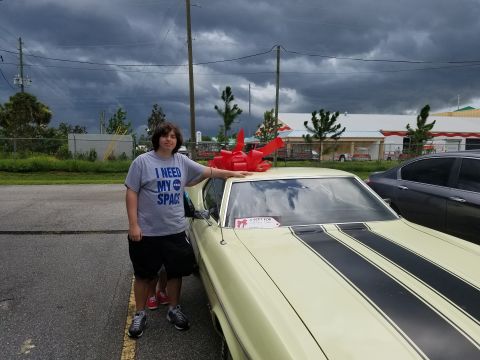 1971 Ford Mustang - Person poses with a 1971 Ford Mustang Mach 1, which has a large red bow on its roof.