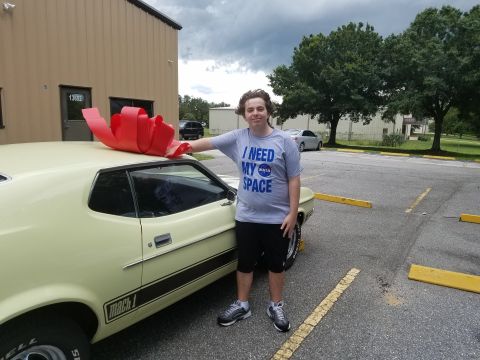 1971 Ford Mustang - A man poses with a newly acquired 1971 Ford Mustang Mach 1, adorned with a large red bow.