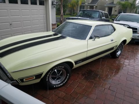1971 Ford Mustang - A 1971 Ford Mustang Mach 1 is parked in front of a garage with two other vehicles behind it.