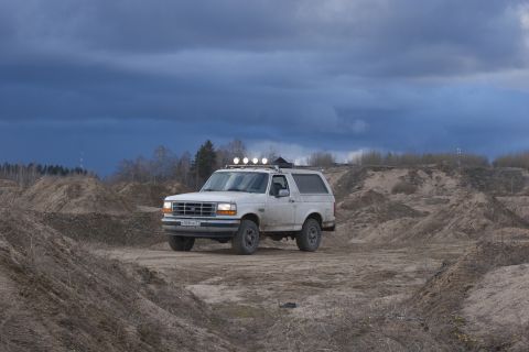 1993 Ford Bronco - White 1993 Ford Bronco is parked on a dirt road with a stormy sky overhead.