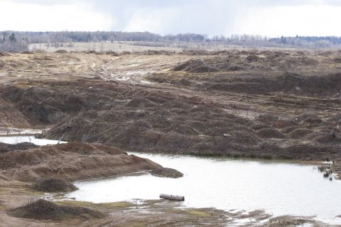1993 Ford Bronco - A desolate landscape with mounds of dirt and a body of water under an overcast sky.