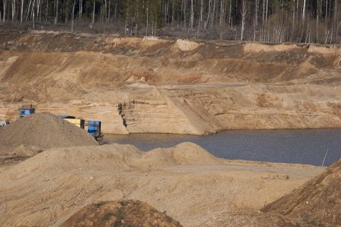 1993 Ford Bronco - Construction vehicles operate in a sand quarry with a body of water and trees in the background.