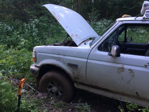 1993 Ford Bronco - This 1993 Ford Bronco is stuck in the mud, with its hood open and a shovel visible.